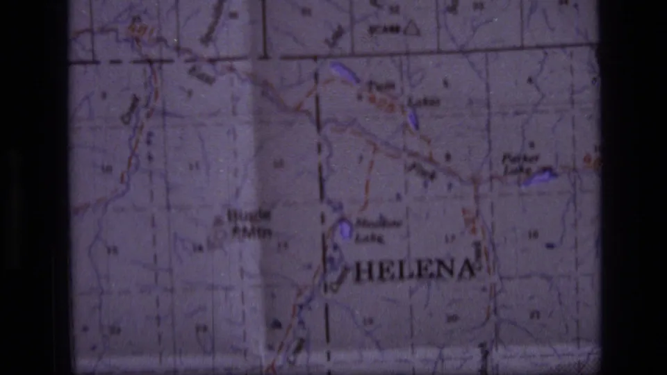 Close 8mm frame of the Helena-area map, showing labeled peaks and park markings in soft focus.