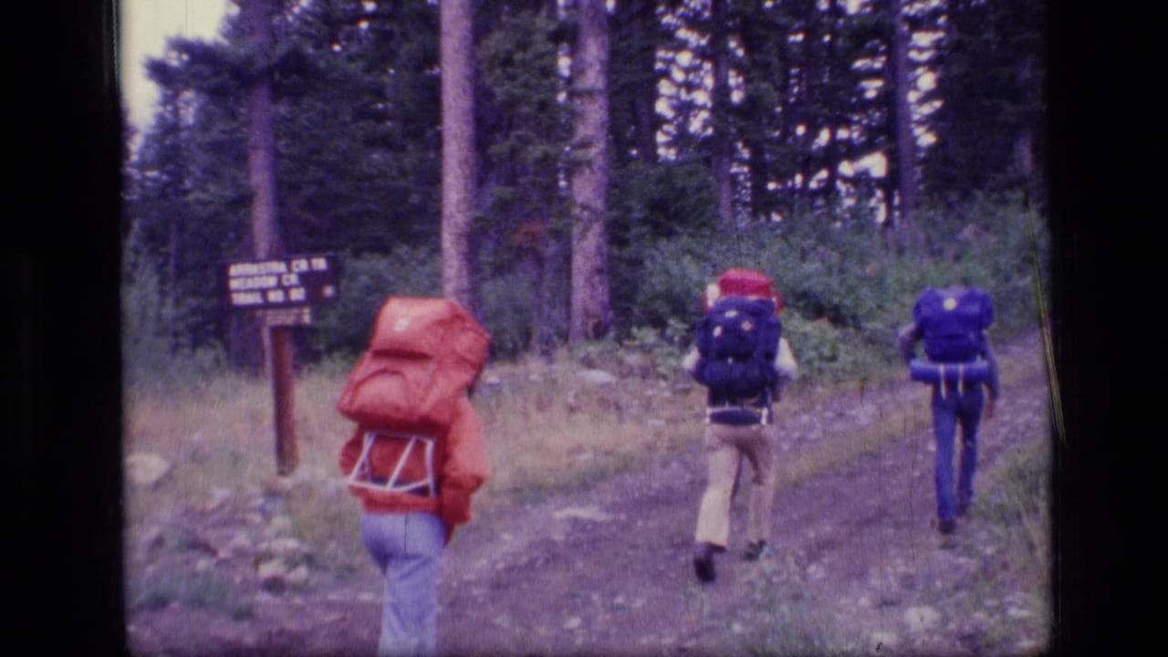 1973 8mm home-movie frame of four backpackers entering a forest trail in Scapegoat Wilderness, Montana.