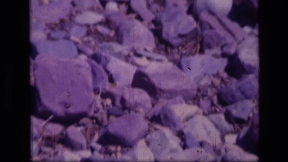 Soft 8mm frame of rocky trail ground in Scapegoat Wilderness with aged color shift and visible film wear.