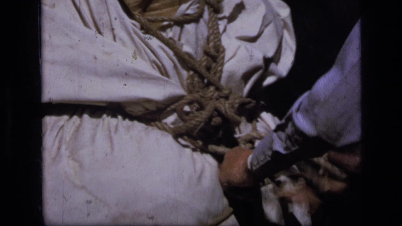 Close view of a white canvas pack tied with thick rope beside a person.