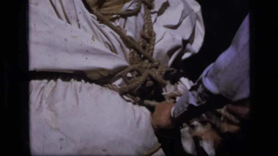 Close 8mm view of a rope-lashed white canvas pack on a pack animal during backcountry preparation in Montana.