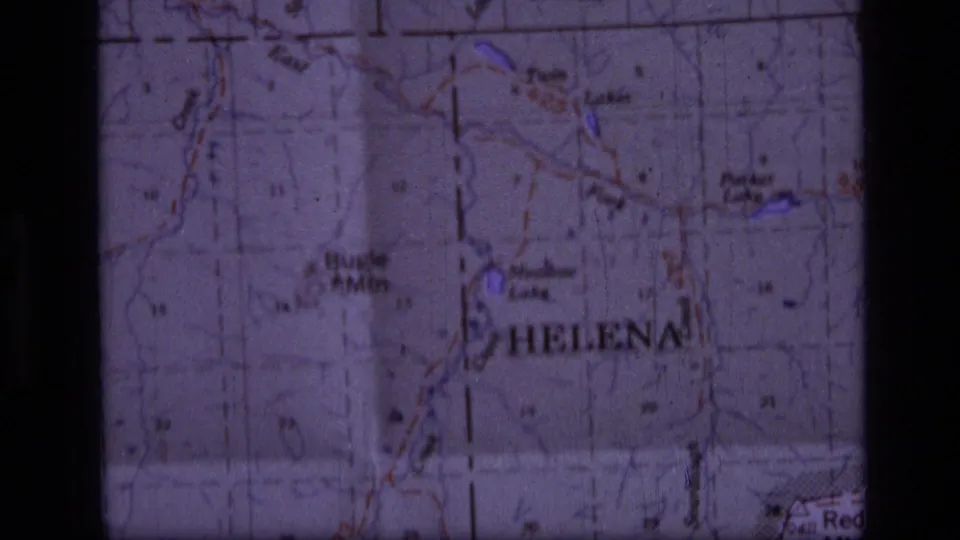 Close view of a paper topographic map with Helena and nearby lake labels visible, used as a hiking route reference.