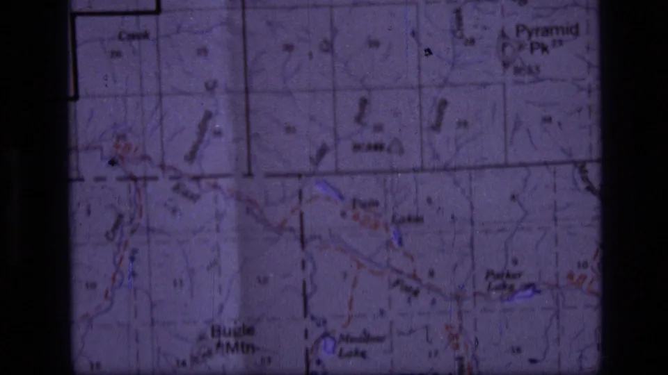 A soft 8mm close-up continues on the Helena-area map, with mountain names and map grid lines visible.