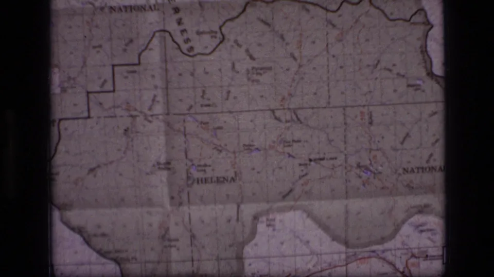 1973 8mm frame of a Montana map showing forest boundary markings, Helena-area labels, and a central dark film divider.