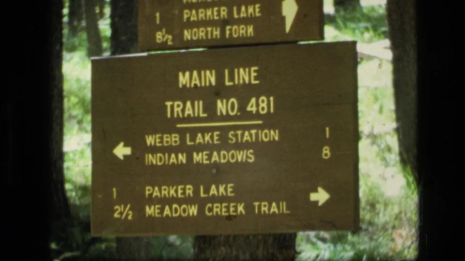 Tight 8mm frame of the Main Line Trail No. 481 wooden marker in Montana, listing Webb Lake Station, Indian Meadows, Parker Lake, and Meadow Creek Trail.