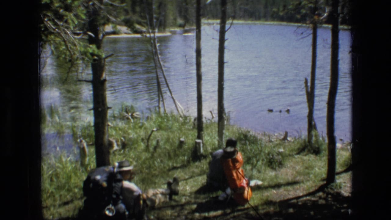 Hikers rest with large backpacks beside a lake in the Scapegoat Wilderness, Montana, supported by the clip metadata.