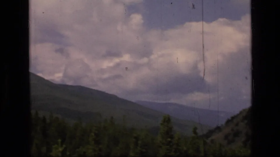 Scapegoat Wilderness mountain view in Montana, showing forested ridges under large clouds on 8mm film.