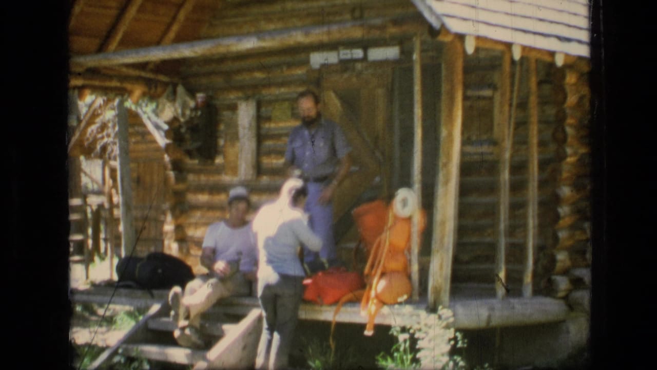 In the Montana wilderness footage, three men stand or sit at a log cabin porch with packs and bright outdoor gear visible.