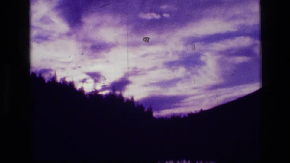 Scapegoat Wilderness 8mm frame with purple clouds, a dark mountain ridge, and a silhouetted forest line.