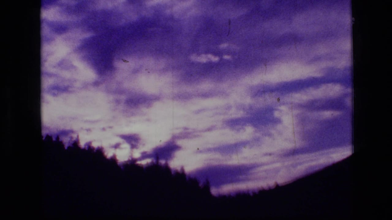 1973 8mm frame from Scapegoat Wilderness showing purple clouds over a silhouetted treeline.