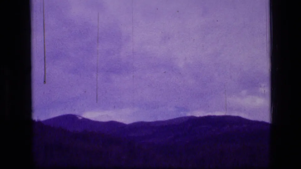 Purple-tinted 8mm mountain landscape with hazy sky and dark ridge line in Scapegoat Wilderness metadata context.