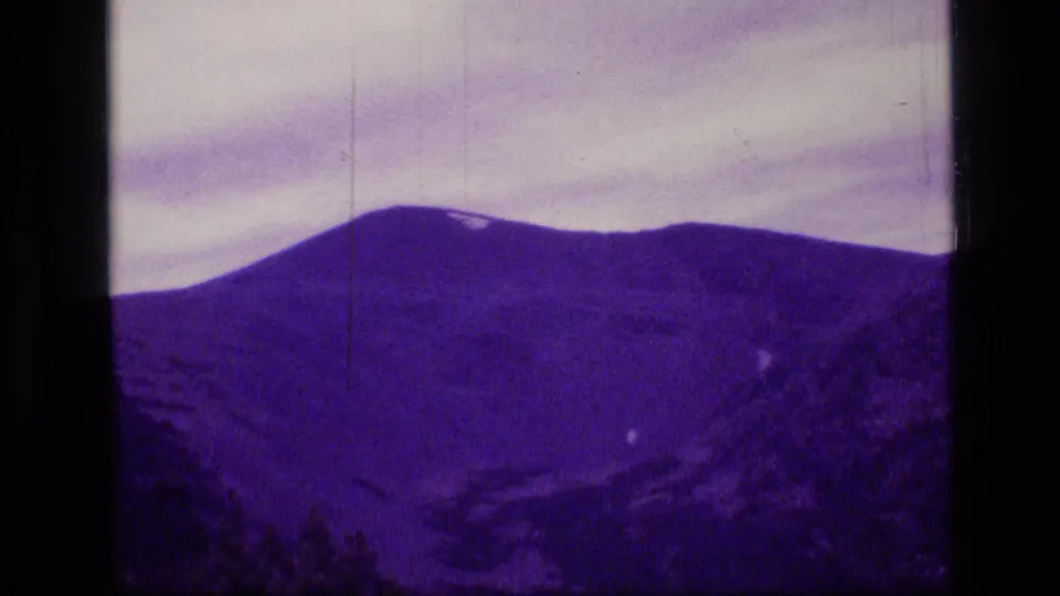 Scapegoat Wilderness ridge under cloud cover, captured on 1973 8mm film with soft focus, grain, and purple color shift.