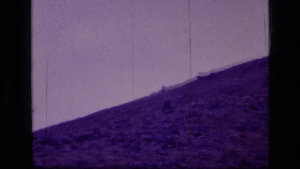 The lone figure continues across the steep Scapegoat Wilderness hillside, seen through soft, scratched 8mm film.