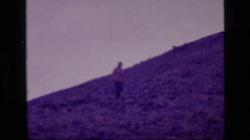 A distant figure descends a rugged mountain hillside in 1973 home-movie footage from Montana's Scapegoat Wilderness.