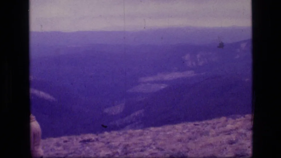 A partly framed hiker exits the shot, leaving a soft purple 8mm view of Montana ridges and rocky foreground.
