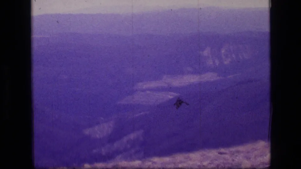 The final frame holds on the Scapegoat Wilderness mountain vista, with rocky ground below and hazy ridges in purple-shifted 8mm color.