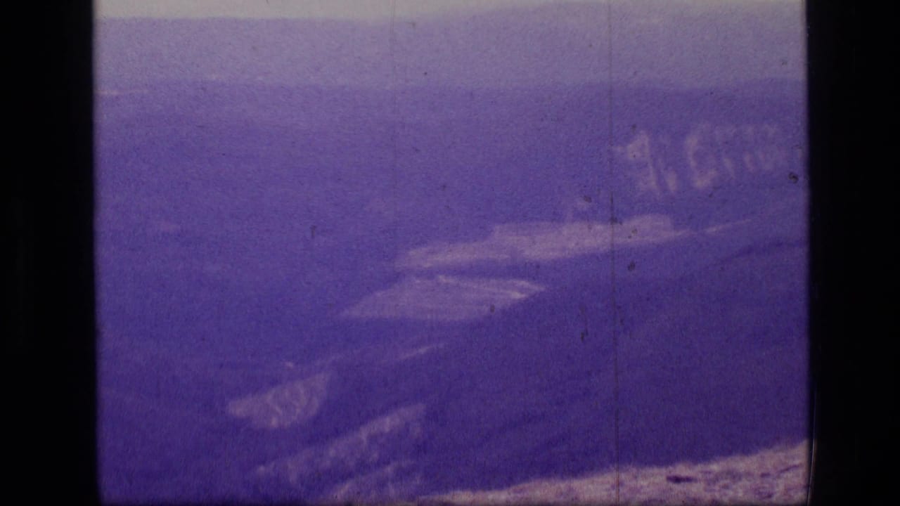 Purple-tinted view across distant mountain ridges and valleys with dark 8mm frame borders.