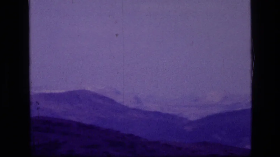 Wide 1973 8mm view of a hazy mountain range in Scapegoat Wilderness, Montana, with a strong purple cast.