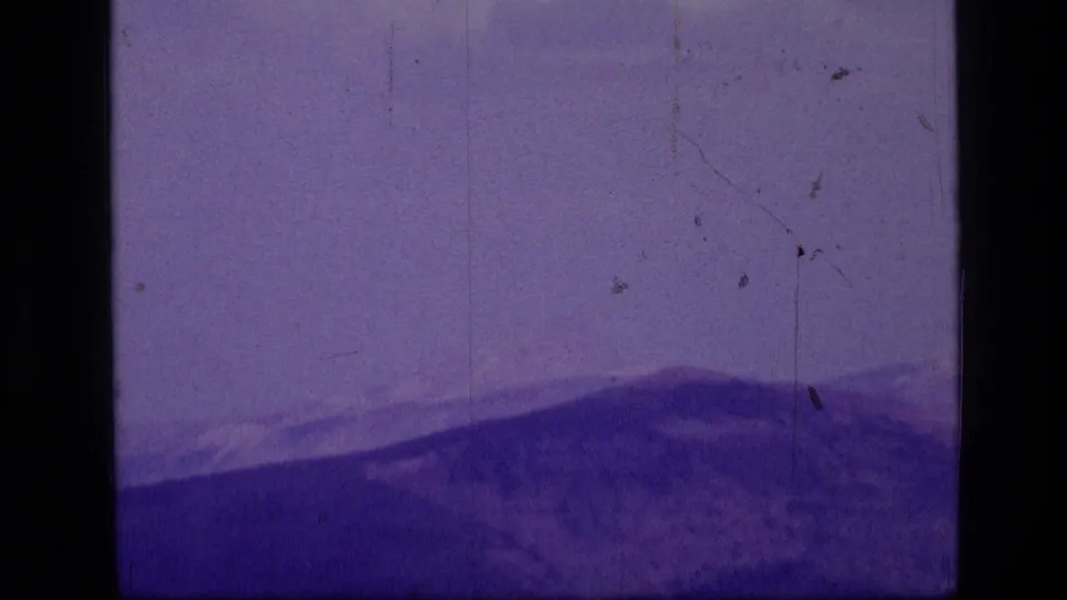Scapegoat Wilderness ridgelines are seen in a purple-tinted 1973 8mm home-movie frame.