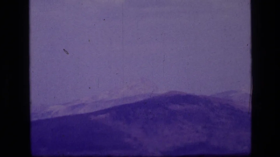 A hazy Montana mountain view appears in a purple-shifted 1973 8mm frame with visible age marks.