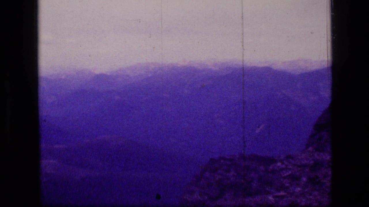 1973 8mm view of Scapegoat Wilderness ridgelines with a rocky foreground and heavy purple color cast.