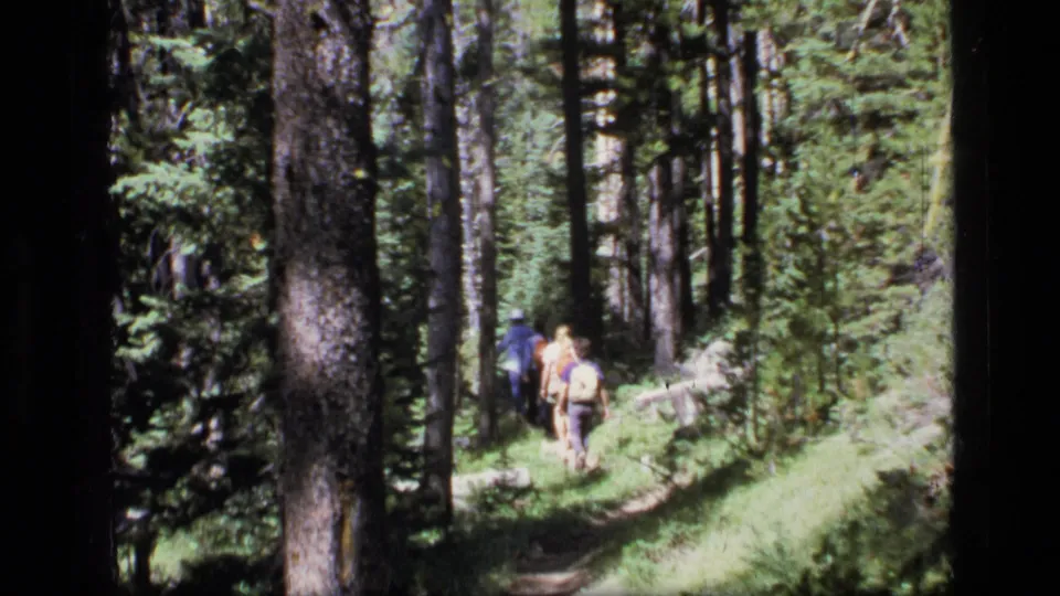 The final frame shows the family group from behind on a narrow Scapegoat Wilderness trail surrounded by evergreen trees and brush.