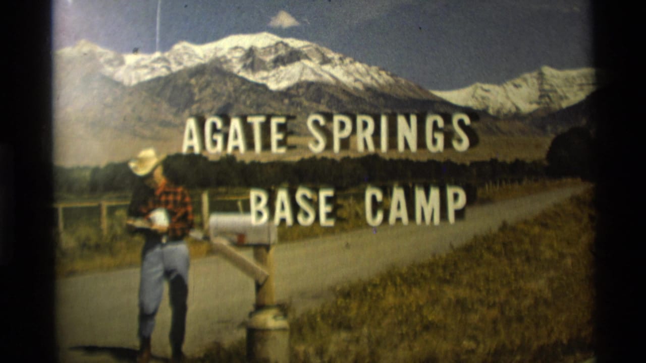 1975 Montana 8mm frame showing a man in a cowboy hat near a roadside mailbox, with Agate Springs Base Camp title text over snow-capped mountains.