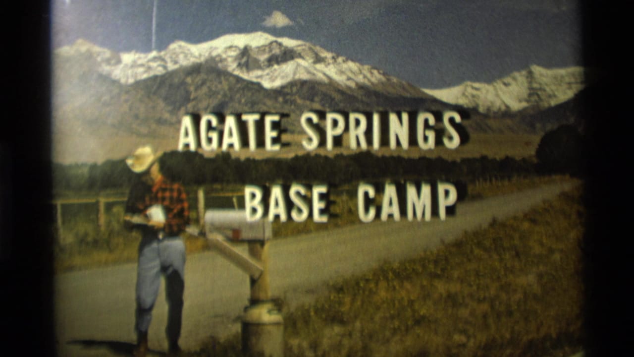 1975 Montana 8mm frame showing a man by a mailbox beneath Agate Springs Base Camp lettering and snow-capped mountains.