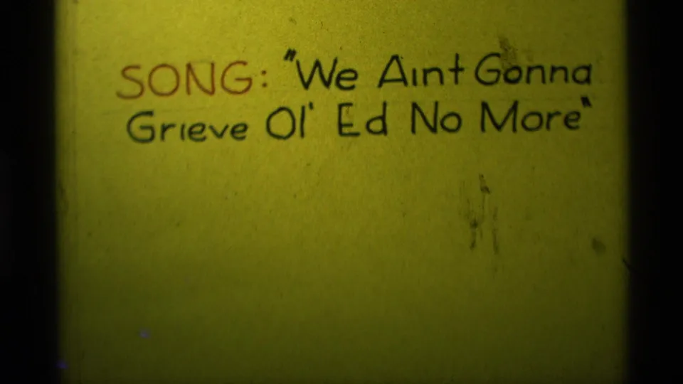 1975 Agate Springs 8mm frame showing a close handwritten song title card on yellow paper with red and black lettering.