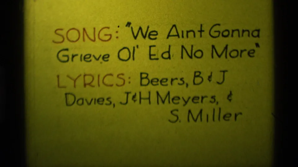 1975 Agate Springs, Montana 8mm frame showing a yellow handwritten song title card with lyric credits in black and red ink.