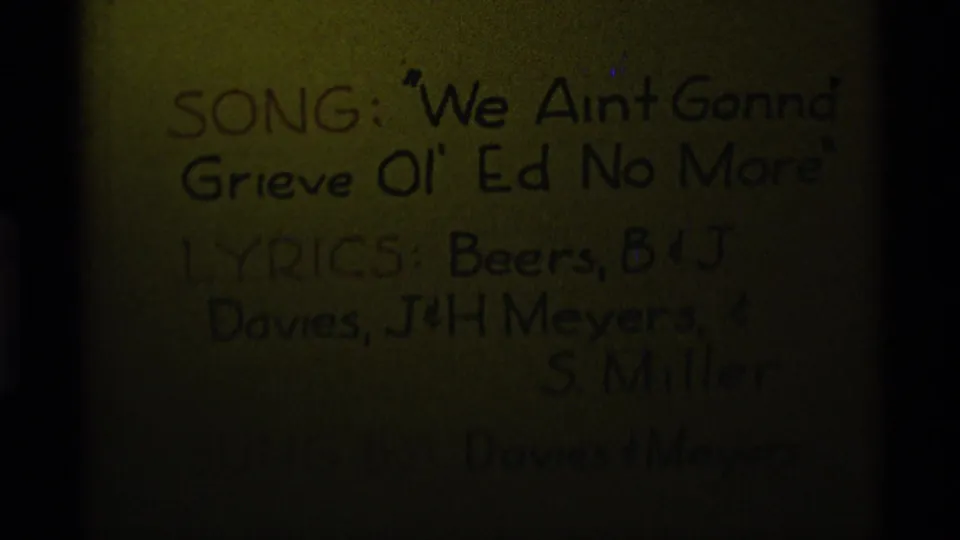 Dark final 8mm frame with the handwritten Agate Springs song title card still faintly visible as exposure drops.
