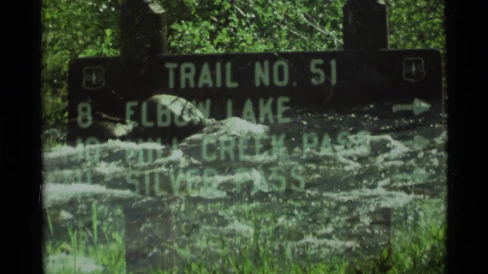 1975 8mm Montana frame with the Trail No. 51 sign partially overlaid by rushing water during a transition.