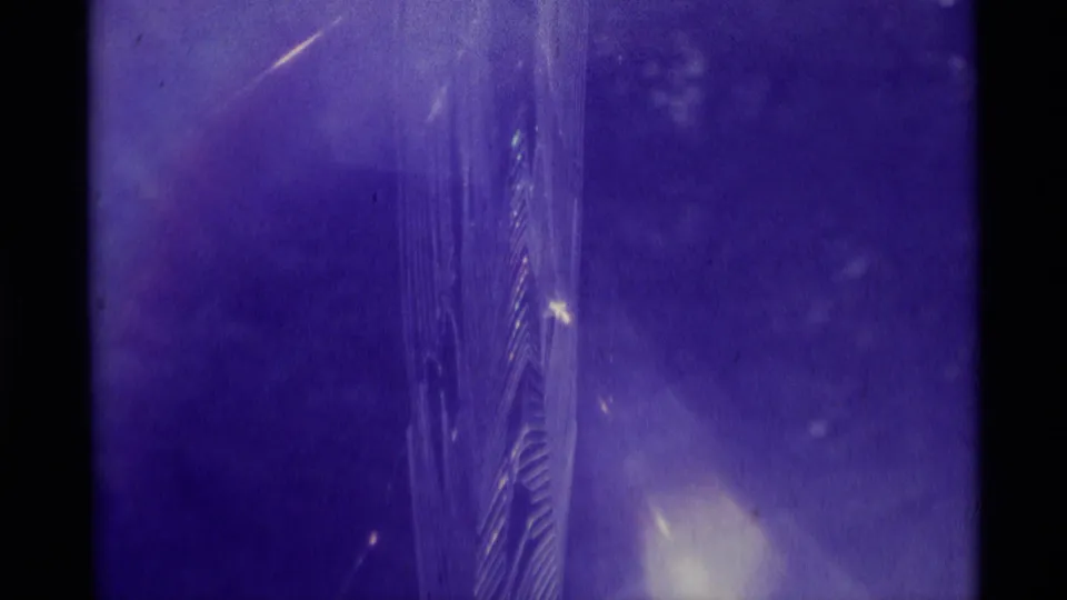 1975 Agate Springs 8mm frame showing fine web strands and purple illumination, with the spider not clearly visible in this extracted still.