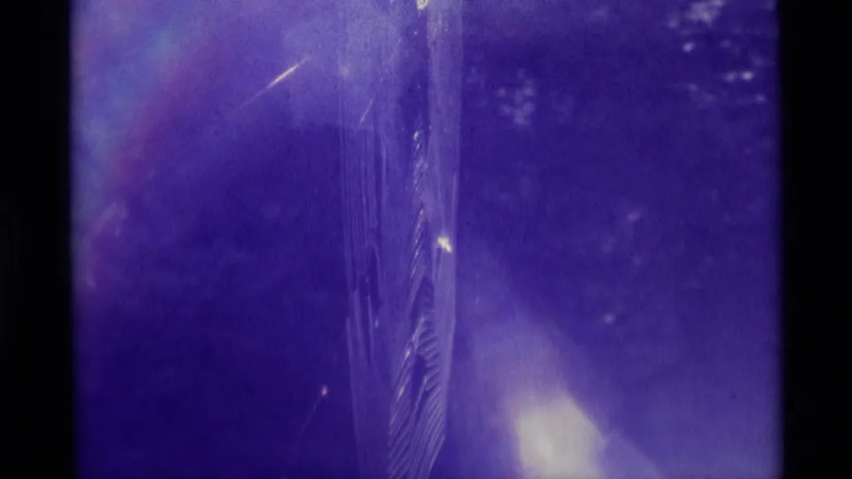 1975 Agate Springs, Montana 8mm footage with a purple cast, central textured vertical form, dark frame edge, flare, dust, and scratches.