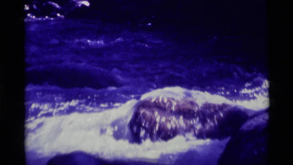 1975 8mm Montana home-movie footage shows turbulent river water and bright foam passing over rounded rocks.