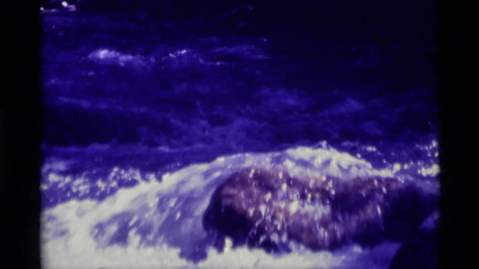 The final 1975 Agate Springs, Montana frame shows white foam and rippling current moving around a central rock in blue-cast 8mm footage.