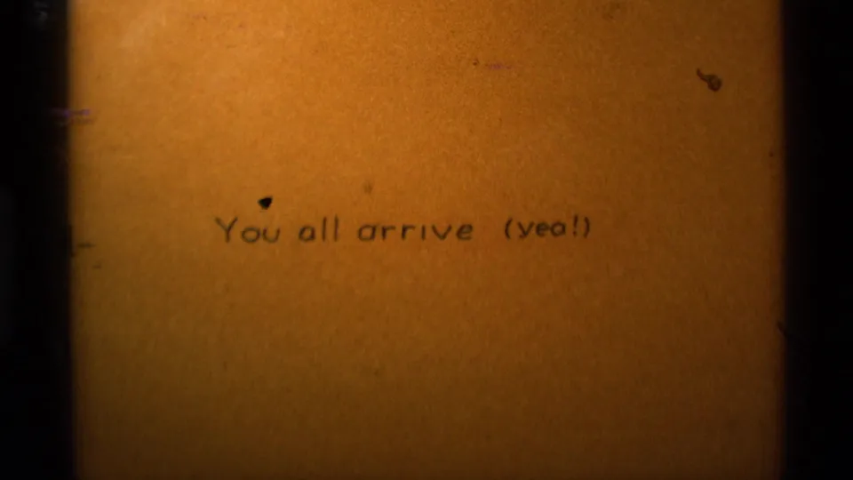 1975 8mm home-movie title frame from Agate Springs, Montana, with handwritten or typed text reading “You all arrive (yea!)”.