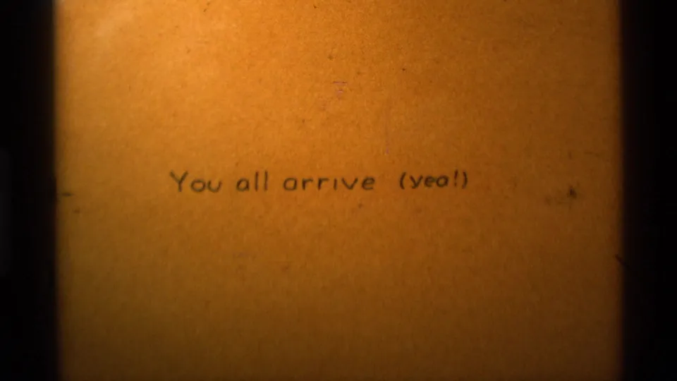 Warm amber 8mm title frame repeats the arrival message, with visible film grain and dark frame edges.