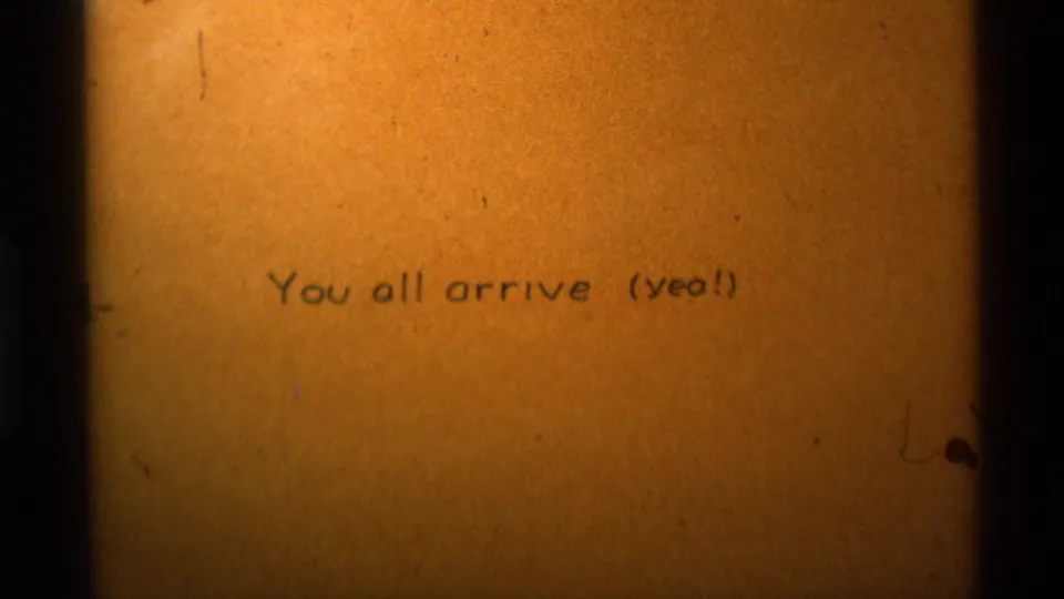 1975 home-movie title frame on amber stock, carrying the arrival note before the outdoor hiking scene.