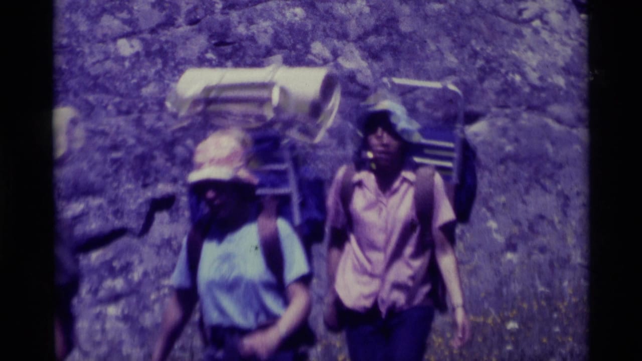Two backpacked hikers in wide-brimmed hats move through dry rocky terrain in Agate Springs, Montana, in 1975 home-movie footage.