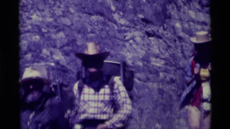 Two hikers pass close to the camera, with a third backpacker partly entering the edge of the 1975 Montana trail frame.
