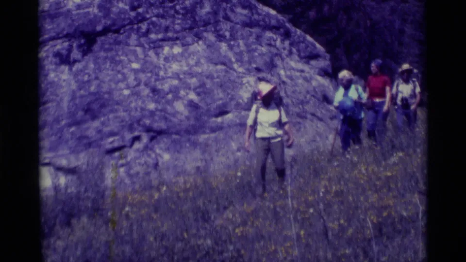 A small backpacking group passes the handheld camera near a rock face in Agate Springs, Montana, in 1975.
