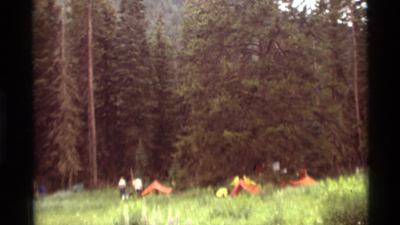1975 8mm home-movie view of a Montana forest campsite with small red and yellow tents in a meadow.