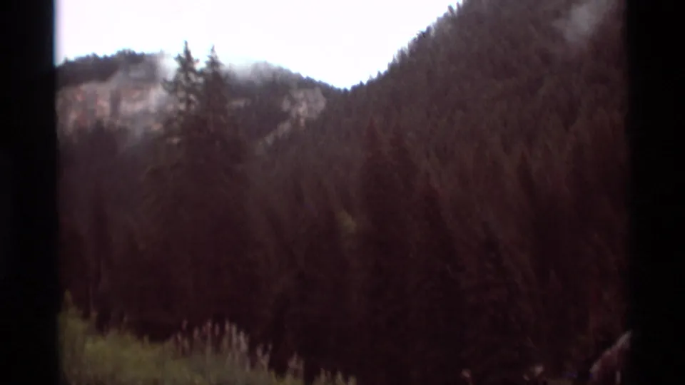 1975 8mm view of forested mountain terrain near Agate Springs, Montana, framed by dark contact-sheet borders.