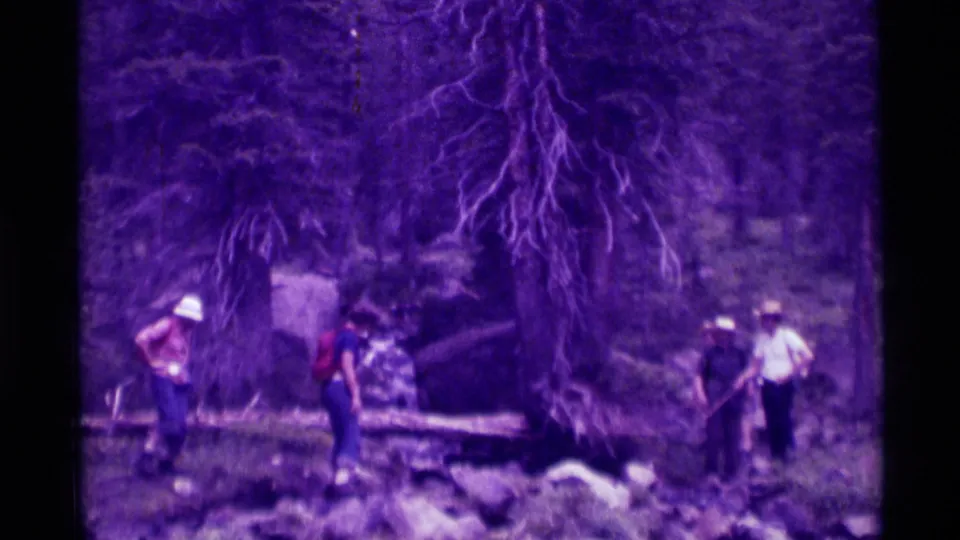 The final 1975 Agate Springs frame shows a small group spread across the wooded stream bank around a fallen log.