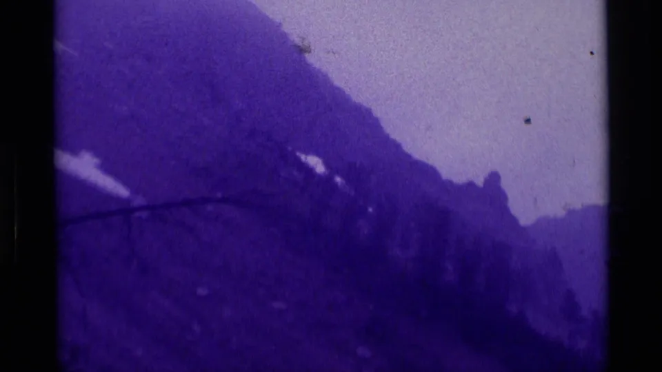 1975 Agate Springs 8mm frame showing a steep misty mountainside, scattered snow, and a distant solitary figure on the slope.