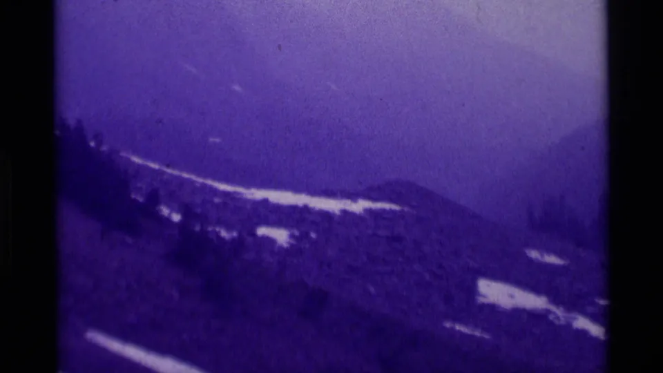 1975 Agate Springs, Montana frame showing a hazy mountain slope with scattered snow patches, dark forest, and visible 8mm frame borders.