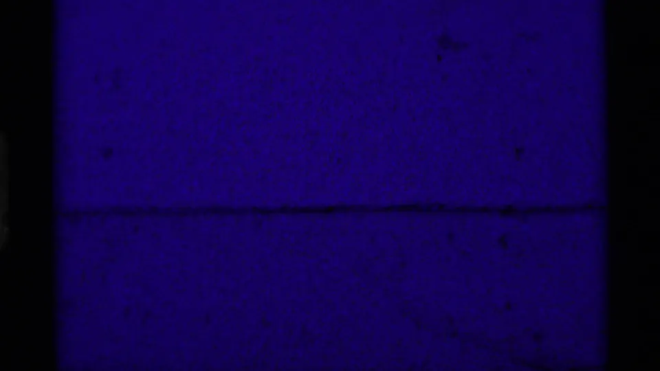 Underexposed final 1975 8mm frame from the Montana clip, mostly blue with faint film texture and frame division.