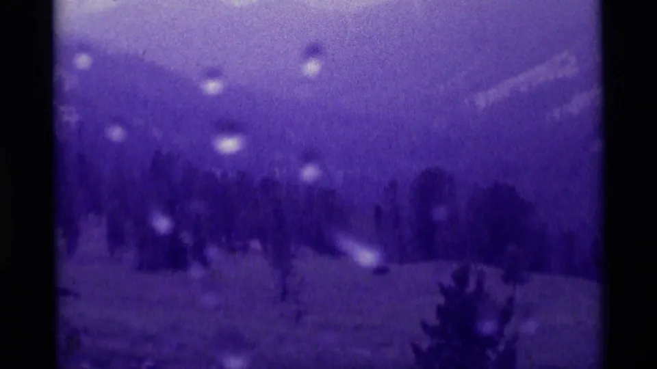 1975 8mm home-movie view in Agate Springs, Montana, showing rain on the lens over soft mountain slopes and a dark tree line.