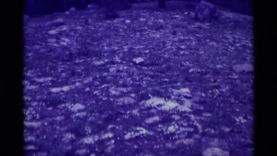 1975 Agate Springs, Montana 8mm frame showing uneven rocky terrain under a dense purple cast, with no people or structures visible.